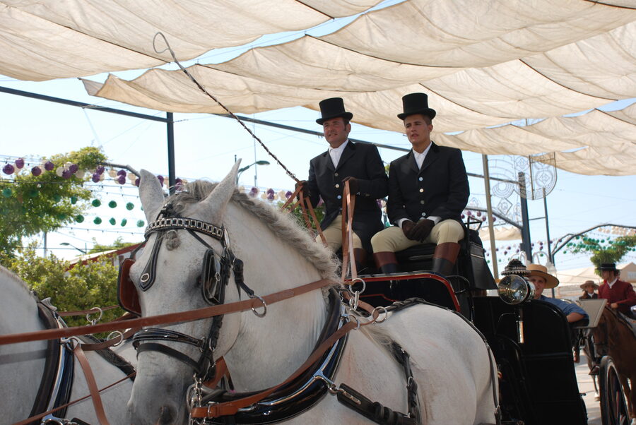 Enganche con dos cocheros de chistera bajo los toldos de la Feria de Málaga