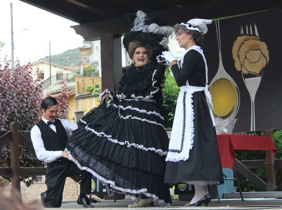 Tres actores caracterizados de época representando una escena sobre un escenario al aire libre