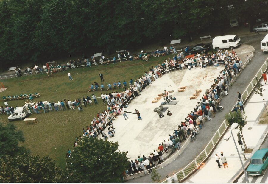 Vista aérea de una plaza con el público rodeando en círculo una exhibición de deporte rural