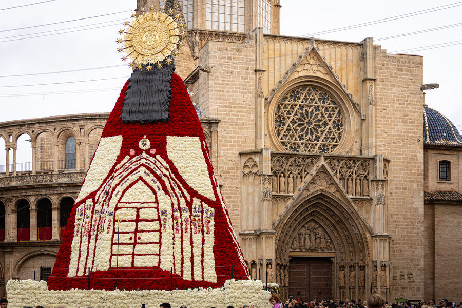 Manto floral con un dibujo geométrico en rojo y blanco montado sobre una estructura delante de una catedral gótica