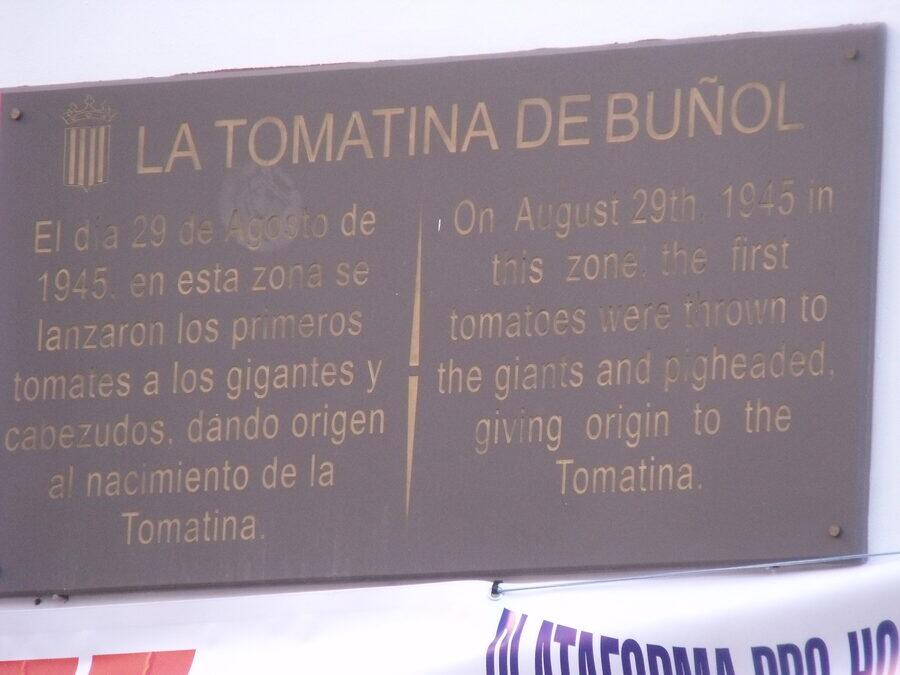 Placa conmemorativa bilingüe que recuerda el origen de la Tomatina de Buñol en 1945